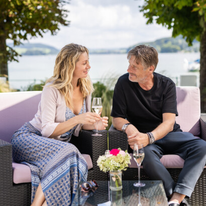 Ein Paar genießt auf der Terrasse am See einen Drink