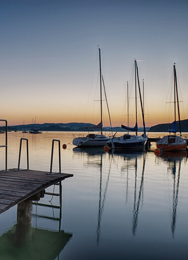 Treibende Boote am Mattsee bei Sonnenuntergang
