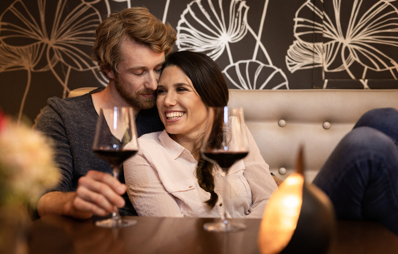 Ein Paar genießt ein Glas Rotwein in der Lounge des Hotels Seewirt Mattsee