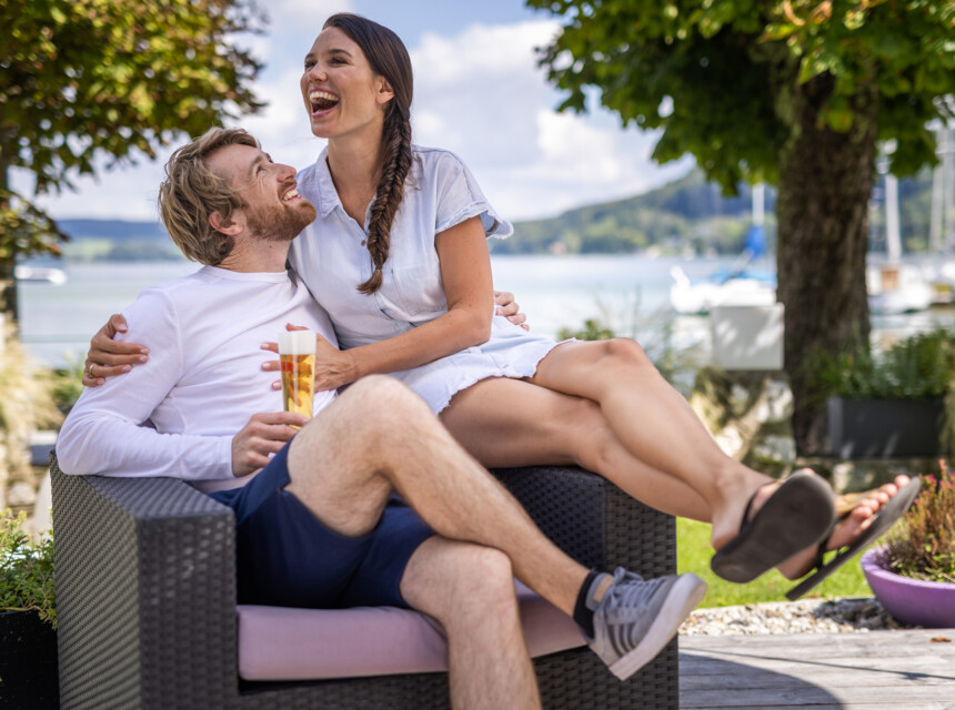 Ein Paar amüsiert sich bei einem Bier auf der See-Terrasse des Hotels Seewirt Mattsee