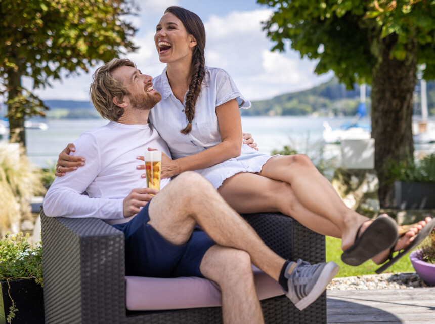 Ein lachendes Paar sitzt beim Urlaub zu zweit in Österreich auf der Terrasse des Hotels Seewirt Mattsee