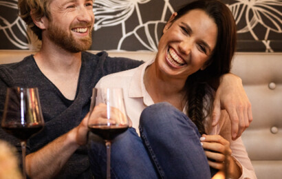 Ein Paar lacht bei einem Glas Wein herzlich miteinander