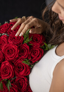 Ein Frau hält einen Strauß roter Rosen