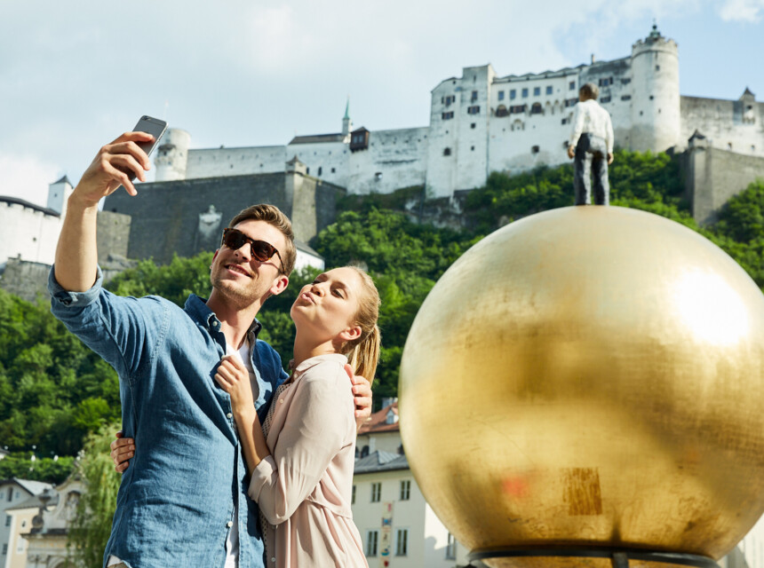 Ein Paar macht ein Selfie mit einer Salzburger Sehenswürdigkeit