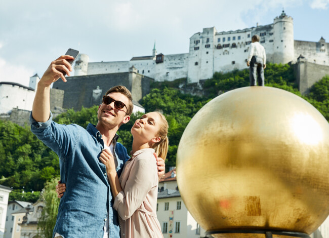Ein macht ein Selfie vor einer Salzburger Sehenswürdigkeit