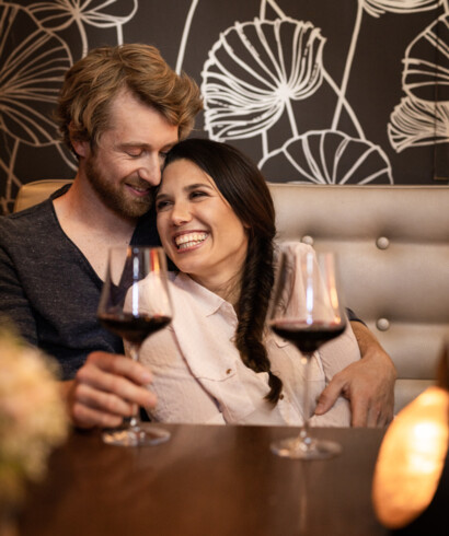 Beim Romantik-Kurzurlaub in Österreich genießt ein Paar ein Glas Rotwein in der Hotelbar
