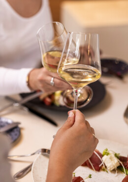 Beim Essen stoßen zwei Gäste mit einem Glas Wein an