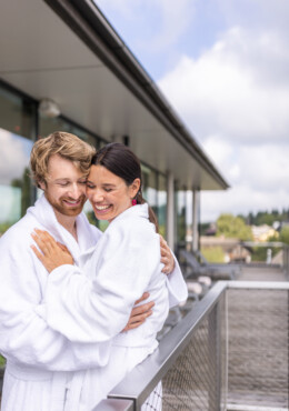 Im Kuschelhotel bei Salzburg umarmt sich ein Paar auf der Terrasse