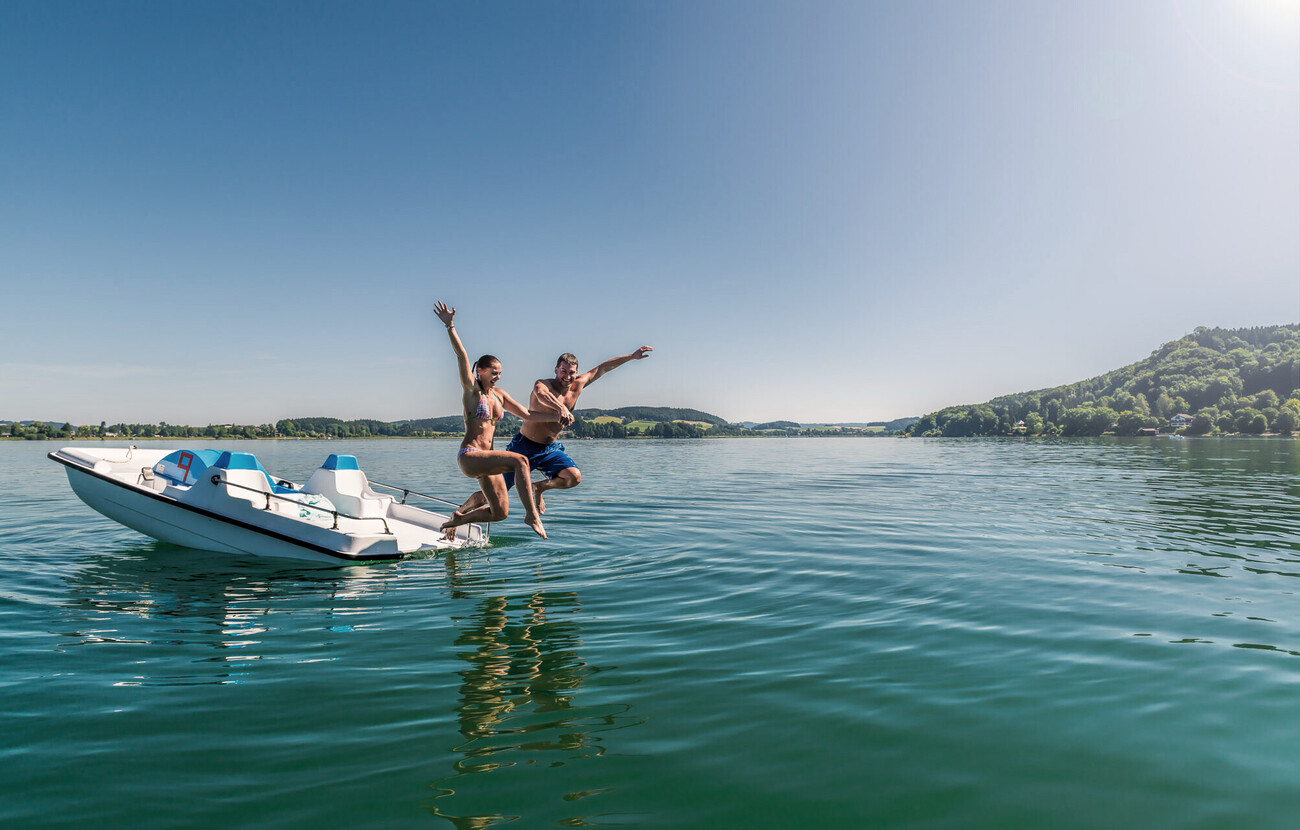 Ein Paar spring von einem Boot aus in den See