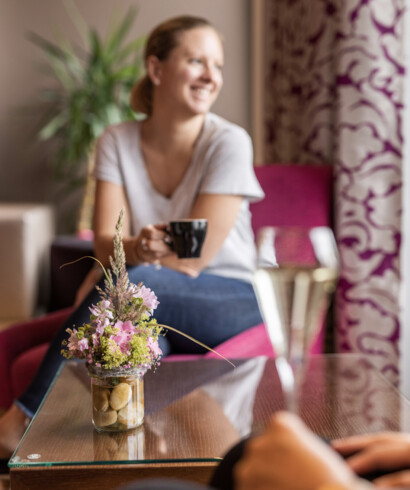 Eine Frau genießt ein der Lounge des Hotels Seewirt Mattsee einen Kaffee