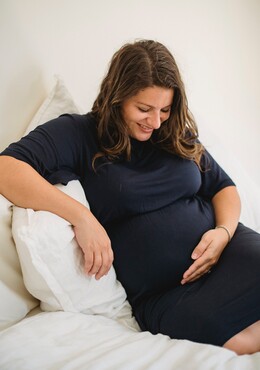 Eine schwangere Frau hält sich liebevoll den Bauch